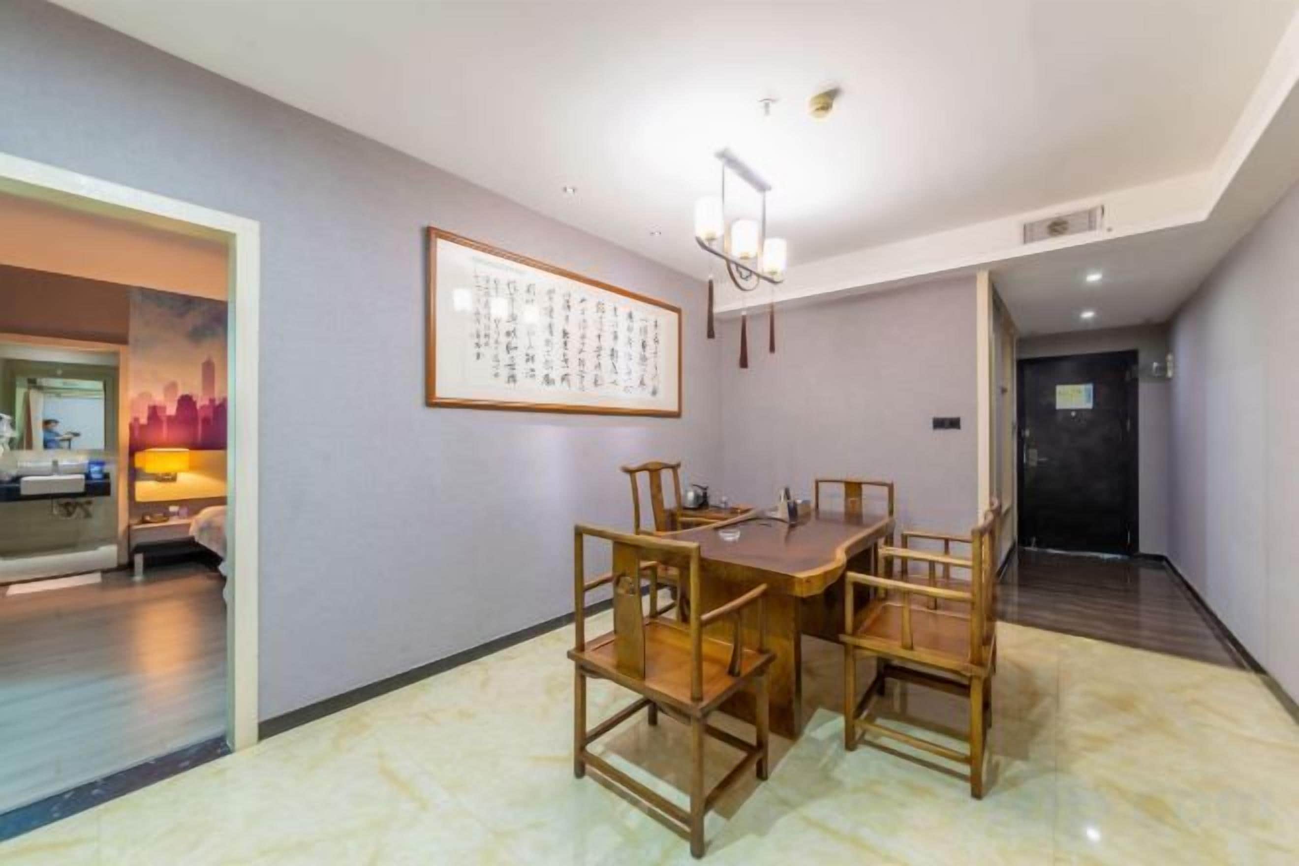 A dining area with a wooden table and chairs, a framed artwork on the wall, and a door leading to another room.
