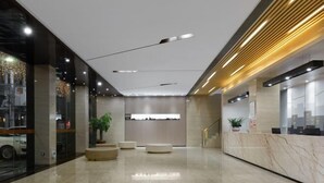 A modern hotel lobby with a reception desk, seating area, and a large window overlooking the street. - Caiyang Hotel (Haifeng)