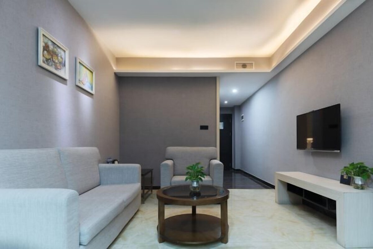 A modern living room with a sofa, armchairs, a coffee table, a TV, and a bench.