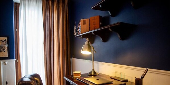 Une pièce comprenant un bureau, une lampe, un ordinateur portable et une étagère avec des boîtes.