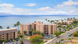 Een hotel aan de kust met meerdere gebouwen, parkeergelegenheid en uitzicht op zee.