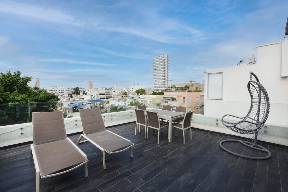 A rooftop terrace with a dining table, two lounge chairs, and a hanging chair.