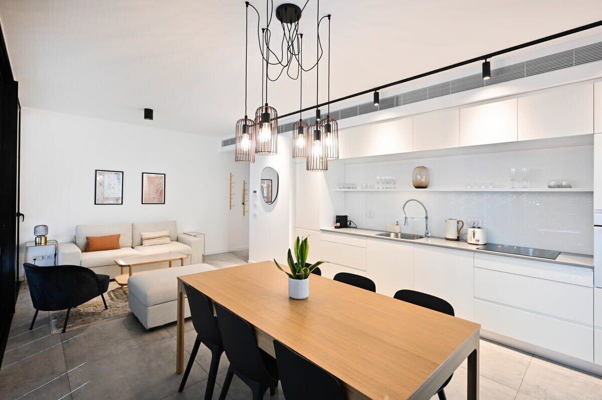 Una cocina moderna con armarios blancos, una mesa de comedor de madera y una silla negra.
