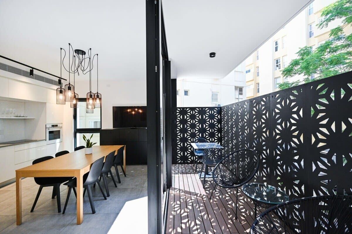 Een moderne keuken met een eetgedeelte, een balkon met een versierd hek en een uitzicht op gebouwen in de verte.