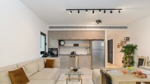 Een moderne keuken met roestvrijstalen apparatuur, een eethoek met een houten tafel en stoelen, en een zithoek met een bank en salontafel.