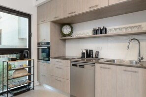 A modern kitchen with light wood cabinets, a stainless steel sink, and a built-in dishwasher. - Stylish 2 BR with Balcony in Ben Yehuda by HolyGuest (Tel Aviv)
