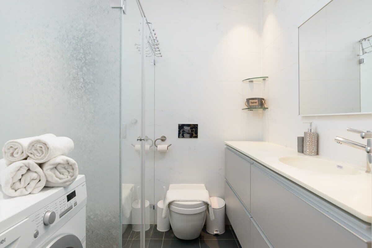 Un baño moderno con lavadora, inodoro, ducha y lavamanos.