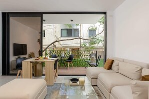 A modern living room with a sofa, coffee table, and a dining area with chairs and a table. - Stylish 2 BR with Balcony in Ben Yehuda by HolyGuest (Tel Aviv)