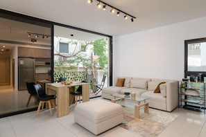 A modern living space with a dining area, sofa, and a glass coffee table.