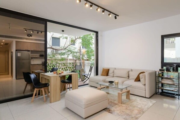 A modern living space with a dining area, sofa, and a glass coffee table.