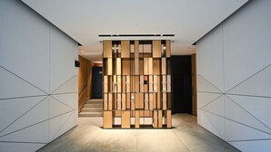 A modern hallway with a geometric patterned wall design and a central wooden partition.