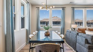 A dining area with a glass table, chairs, and a chandelier. - Desert Beach Retreat: Desert Color Lagoon + Beaches (St. George)