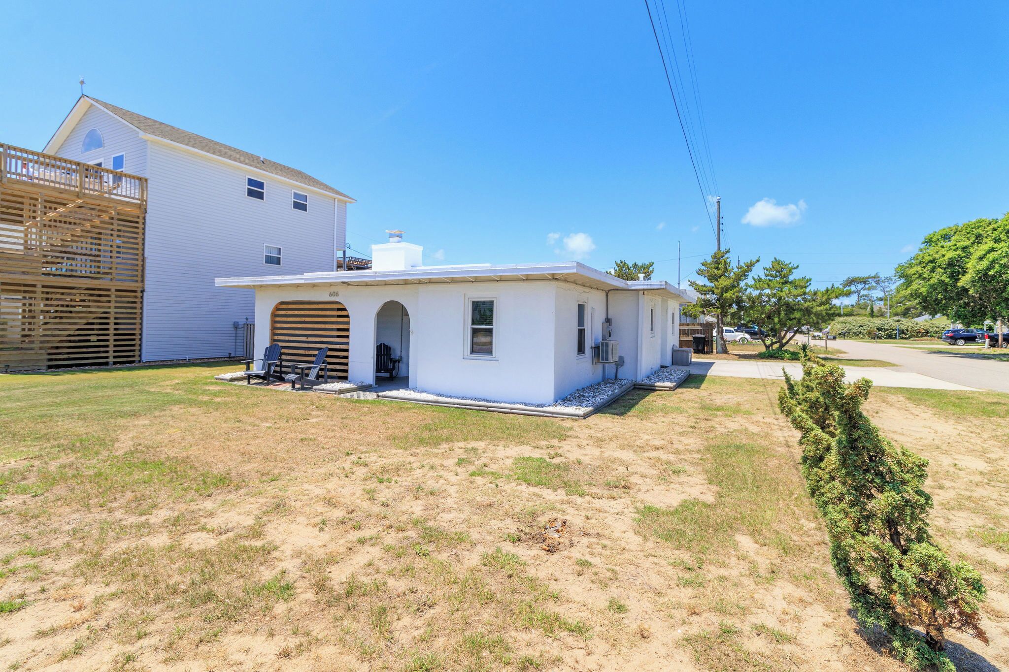 A single-story house with a garage, a small porch with two chairs, and a well-maintained lawn.