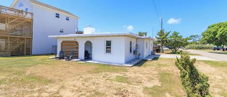 A single-story house with a garage, a small porch with two chairs, and a well-maintained lawn.