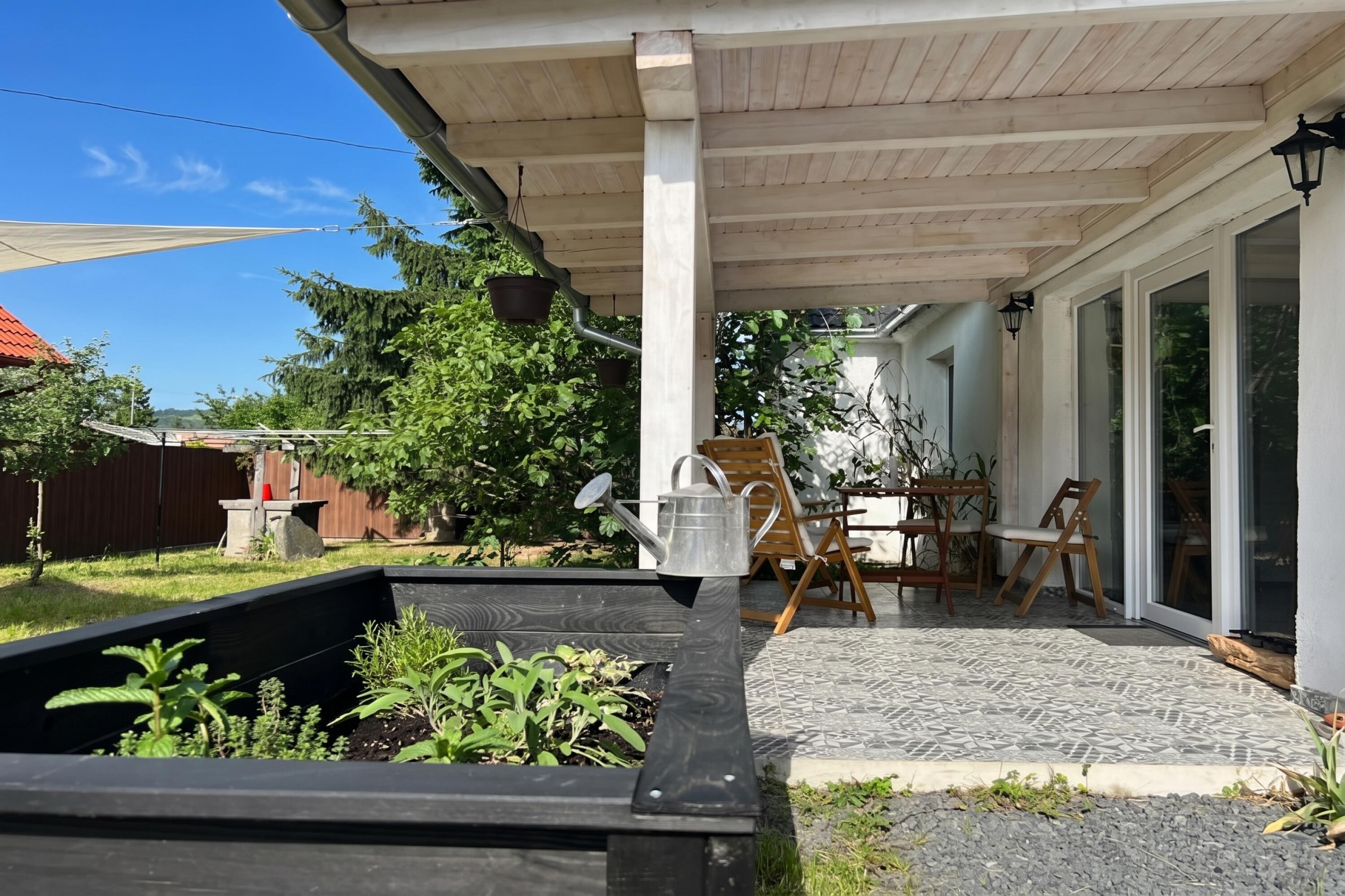Un patio techado con jardín, mobiliario exterior y vista al jardín trasero.