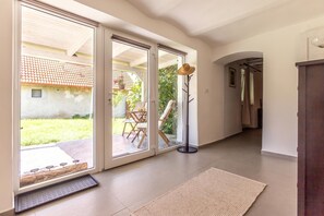 A hallway with a sliding glass door leading to a patio, a wooden floor, and a rug.