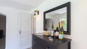 A room with a dark wooden dresser, a large mirror, and two wine bottles on top.
