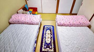Una habitación con dos camas, cada una con un cojín rosa y una colcha acolchada. Un tapete decorativo azul se encuentra entre las camas.