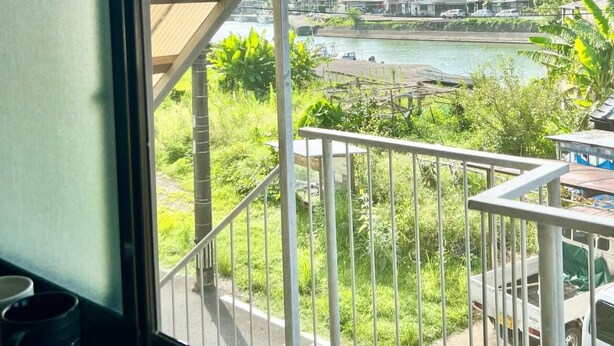 A balcony with a view of a river, buildings, and greenery.