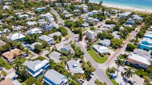 An aerial view of a coastal residential area with houses, a beach access road, and a beach in the background. - Beautiful villa with Private Pool, short stroll to beach w/ beach gear and grill (Holmes Beach)