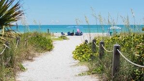 A sandy path leading to beach chairs and umbrellas under a canopy. - Beautiful villa with Private Pool, short stroll to beach w/ beach gear and grill (Holmes Beach)