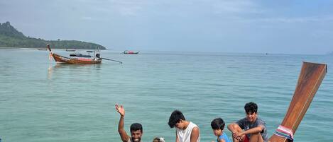 A wooden boat with people sitting on it, a calm sea, and a distant island.