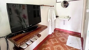 Een kleine badkamer met een televisie aan de muur, een wastafel en een vloer met een patroon.