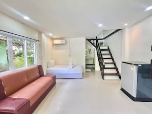 A modern living space with a sofa, a bed, a staircase, and a refrigerator. - Koh mook garden beach resort   (Ko Mook)