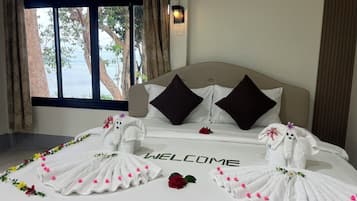 A hotel room with a bed, a window with curtains, and a welcome mat.