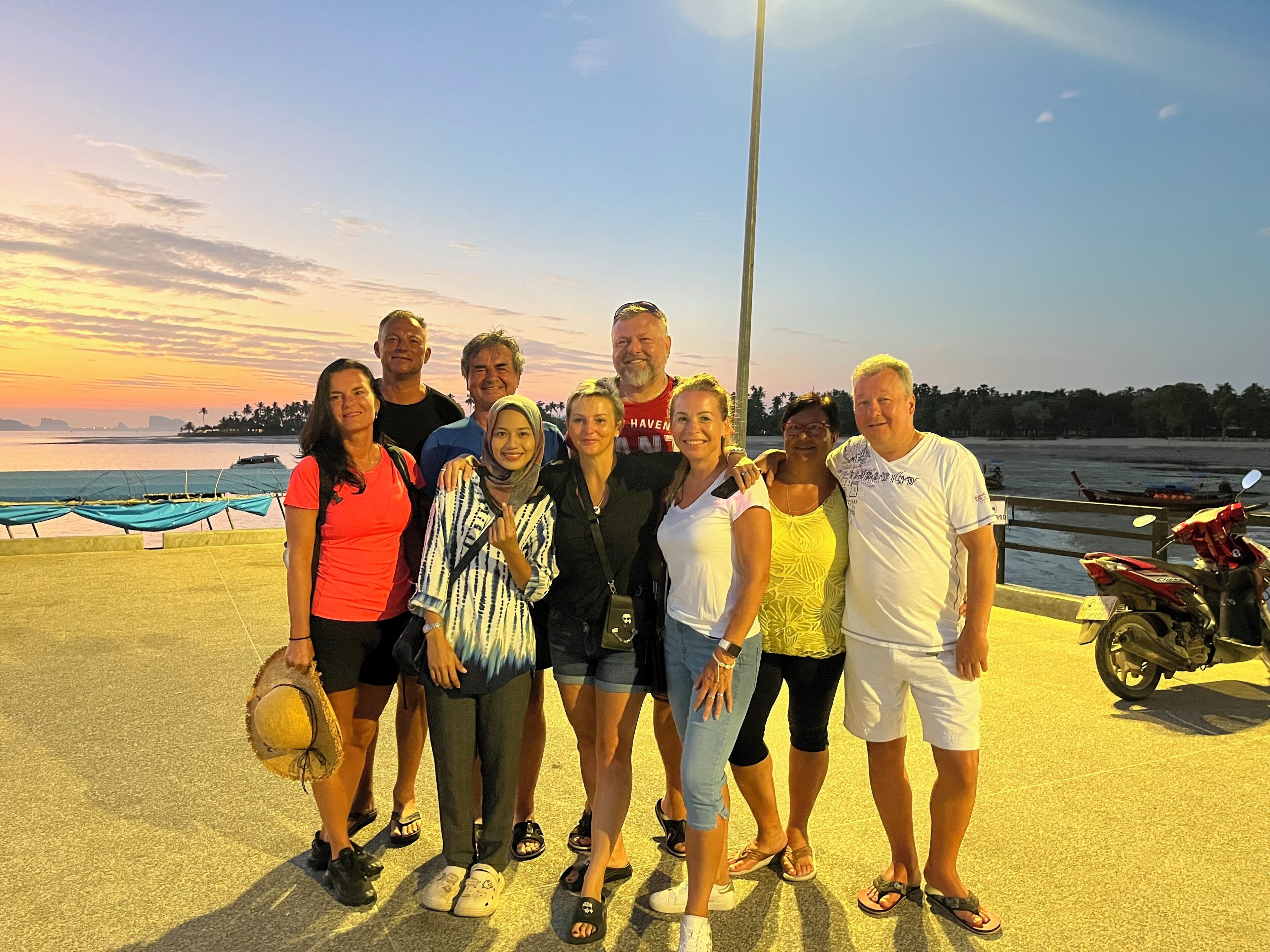 A group of people standing on a concrete surface with a sunset in the background.