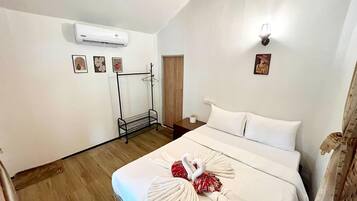 Habitación de hotel con cama, perchero, equipo de aire acondicionado y lámpara de pared.