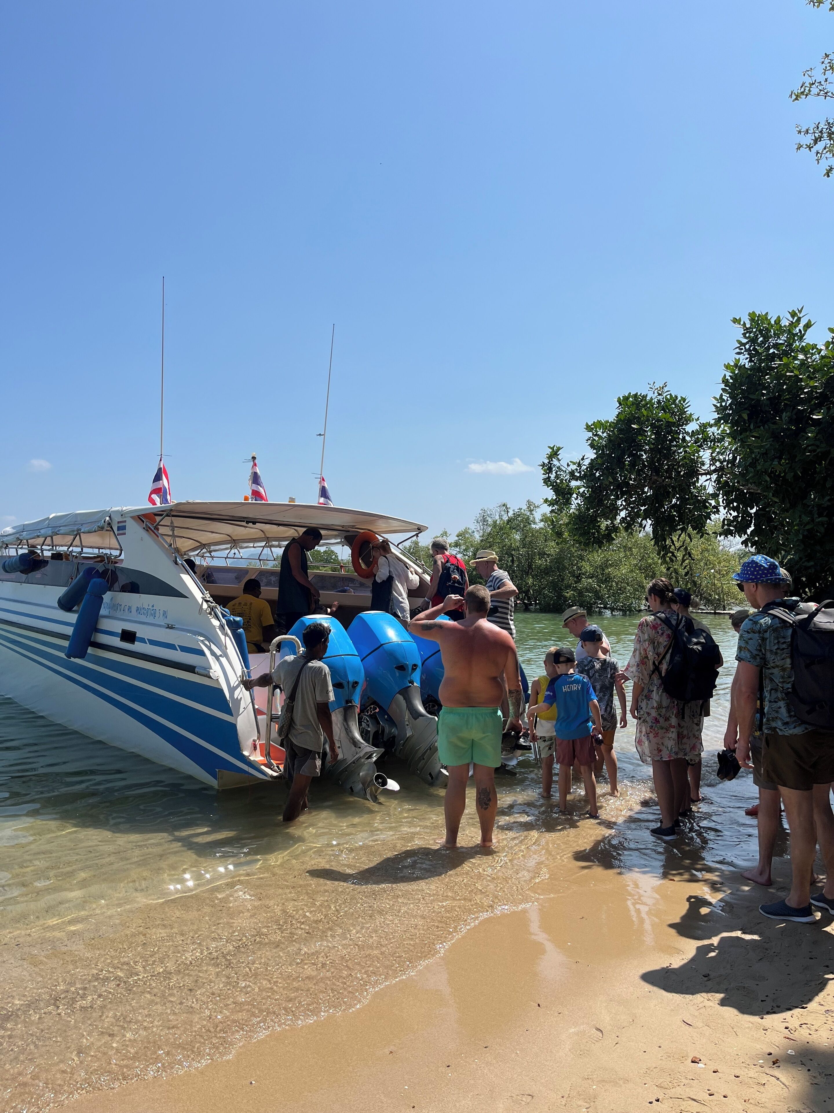A boat docked at a beach with people boarding and disembarking.