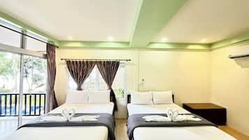 A hotel room with two beds, a balcony, and a view of trees.