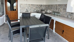 A modern kitchen with a dining area, featuring a large island, a built-in stove, and a patterned backsplash. - El Valle Verde - Perfect Family Retreat (Monte Pego)