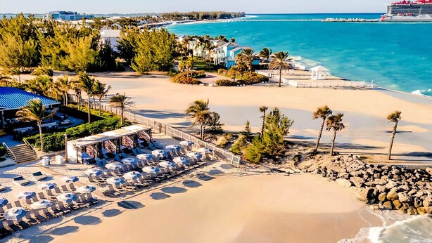 Un resort sulla spiaggia con lettini, piscina e vista sull'oceano.