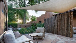 An outdoor patio with stone flooring, a wooden fence, and a shaded area.