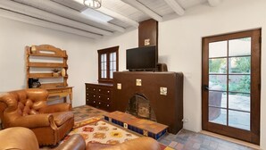A living room with a fireplace, leather sofa, wooden shelves, and a television.