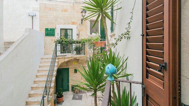 A narrow alleyway with a staircase, a wooden door, and potted plants. - Polly House by Wonderful Italy (Polignano a Mare)