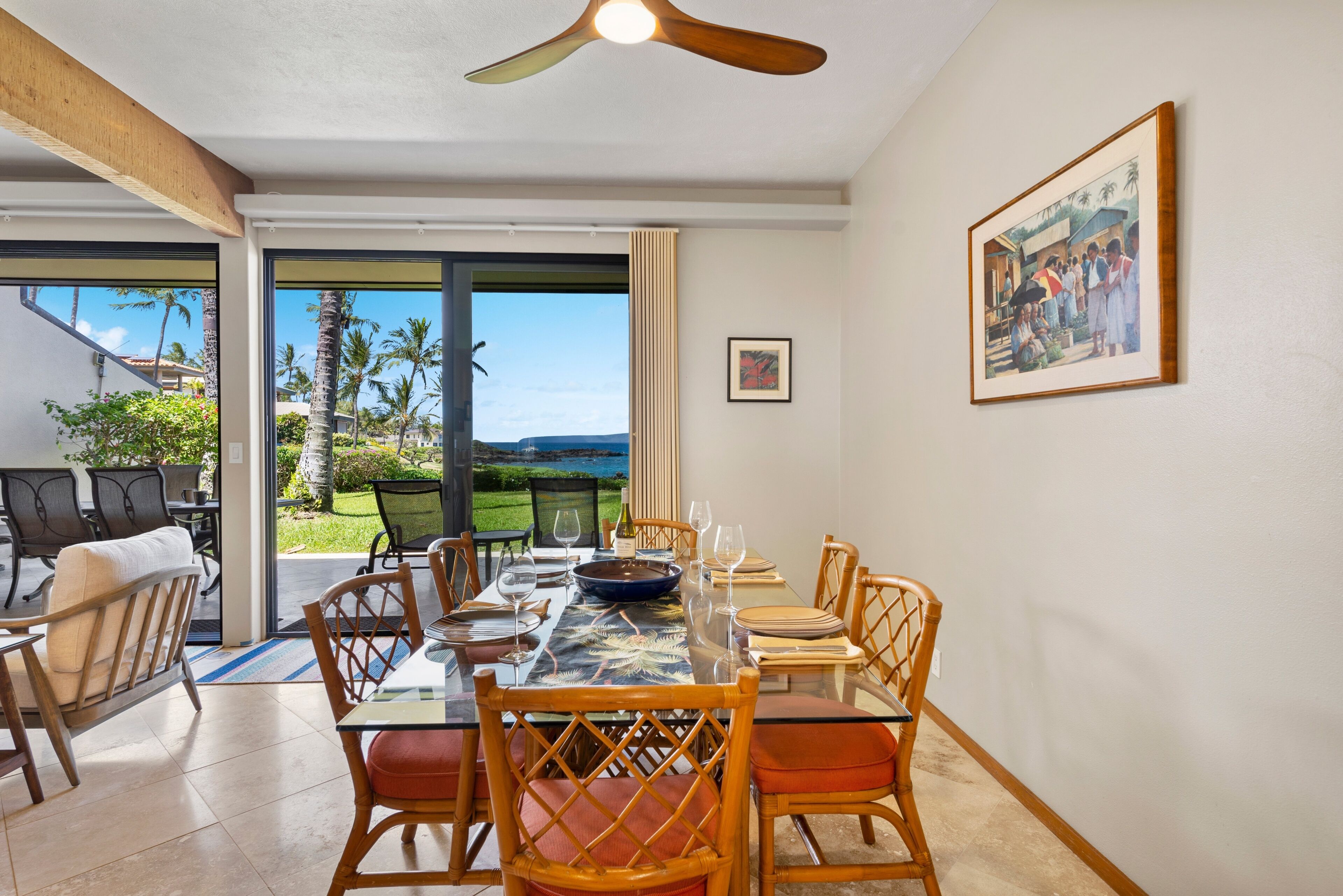 A dining area with a table set for four, overlooking a scenic view of palm trees and a body of water.