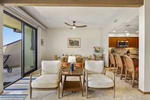 A dining area with wicker chairs, a table with a lamp, and a ceiling fan. - Makena Surf, #g-103 2 Bedroom Condo by RedAwning (Kihei)