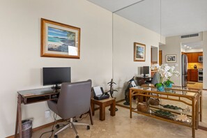 Une chambre d’h ôtel équipée d’un bureau, d’une chaise, d’un ordinateur et offrant une vue sur la cuisine.