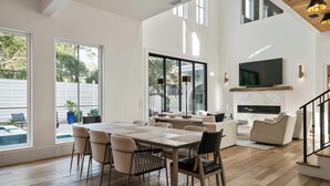 A spacious living area with a dining table, sofas, and a TV mounted on the wall. - Luxury Seagrove w Pool, Hot Tub, Golf Cart & Bikes, Elevator (Seagrove Beach)