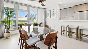 A modern kitchen with a large island, a dining area with a glass table, and a ceiling fan. - Stunning New 3/2 Condo, near Beach & SJ Airport. 2 Pools, WiFi, AC  (Carolina)