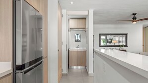 A modern kitchen with a stainless steel refrigerator, wooden cabinets, and a white countertop. - Stunning New 3/2 Condo, near Beach & SJ Airport. 2 Pools, WiFi, AC  (Carolina)