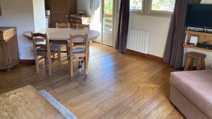 A spacious living area with a wooden dining table, chairs, a sofa, and a television. - 71m² apartment near Megève, 180m from 🚠 La Princesse, parking, ski room (Demi-Quartier)