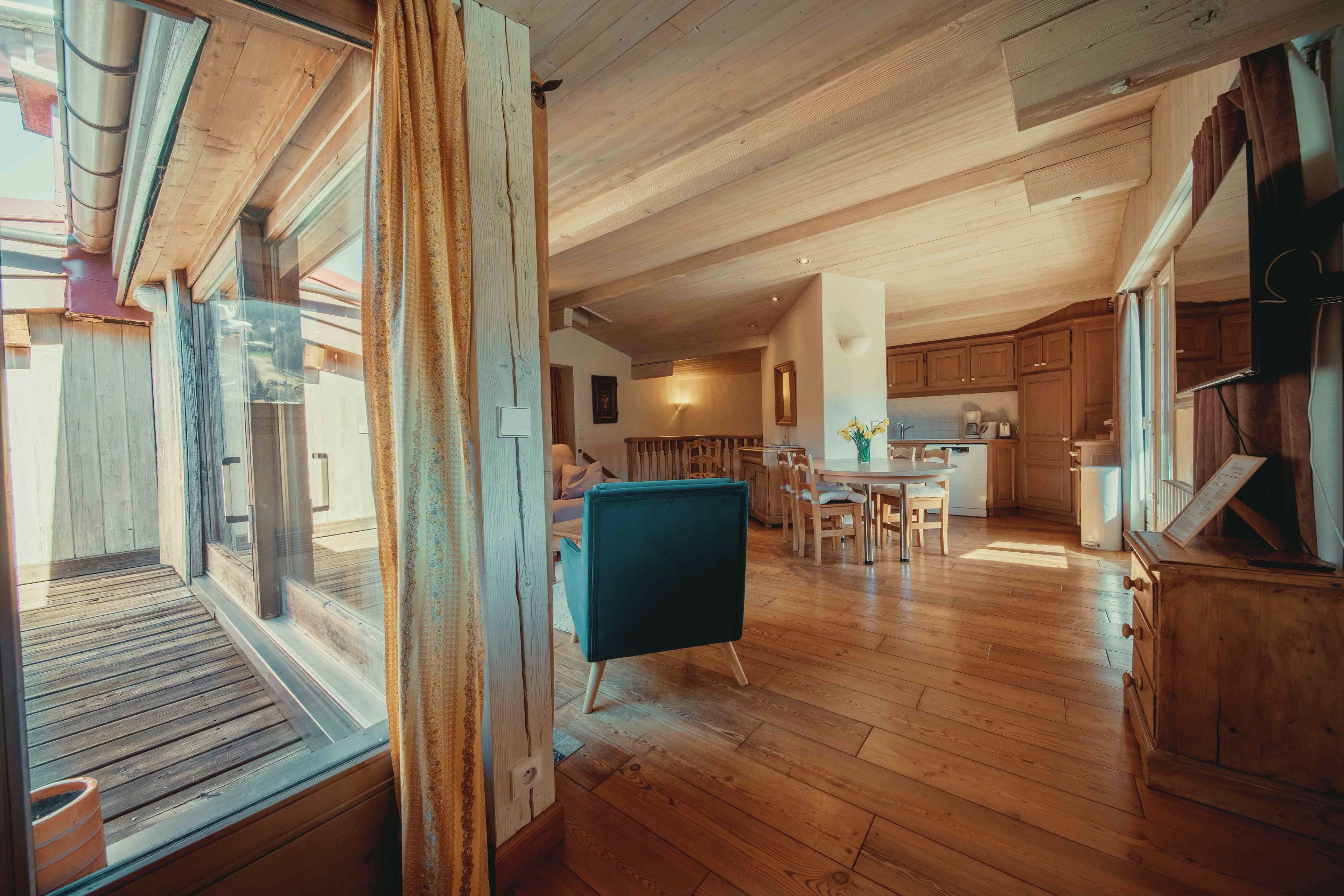 A spacious kitchen with wooden cabinets, a dining area with a table and chairs, and a large window with curtains.