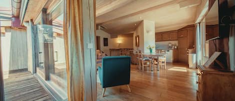 A spacious kitchen with wooden cabinets, a dining area with a table and chairs, and a large window with curtains.