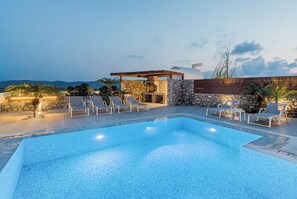 A swimming pool with lounge chairs and a stone wall. - Luxury Villa with Private Swimming Pool, BBQ, playground, 5 min. from Prasonisi! (Rhodes)