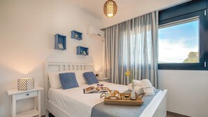 Een netjes ingerichte slaapkamer met een bed, nachtkastjes, een raam met gordijnen en een wandairconditioner.