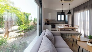 Een moderne keuken met een eethoek, een groot raam en uitzicht op groen.